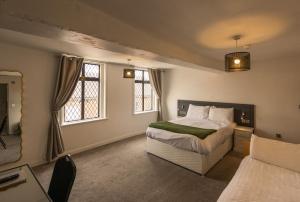 a bedroom with a bed and two windows at The White Hart Hotel in Uttoxeter