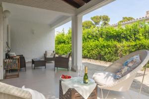 een patio met stoelen en een tafel met een fles wijn bij Villa Campins in Port d'Alcudia