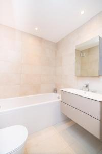 uma casa de banho com uma banheira, um WC e um lavatório. em Whitfield Street Apartments em Londres