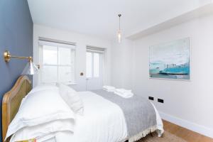 a white bedroom with a bed and a painting at Whitfield Street Apartments in London