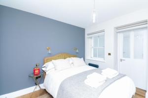 um quarto azul com uma cama grande e almofadas brancas em Whitfield Street Apartments em Londres