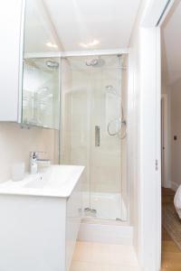 a white bathroom with a shower and a sink at Whitfield Street Apartments in London