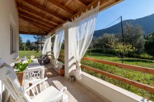 a porch with white chairs and a view of the mountains at Kapella Country House in Vátos