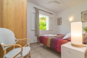 een slaapkamer met een bed, een stoel en een raam bij Villa Campins in Port d'Alcudia