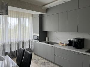 een keuken met witte kasten en een tafel met stoelen bij Dendrarium Park Apartment in Chişinău