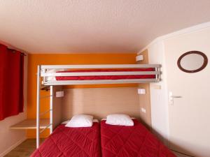 a bedroom with two bunk beds with red sheets at Premiere Classe Metz Nord - Semecourt in Fèves