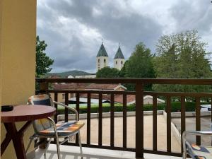 a balcony with a table and chairs and a church at Pansion Mate & DDS in Međugorje