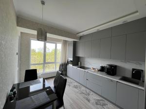 a kitchen with white cabinets and a table and a window at Dendrarium Park Apartment in Chişinău