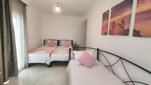 1 dormitorio con 2 camas con almohadas rosas y sofá en First line apartment, en Flogita