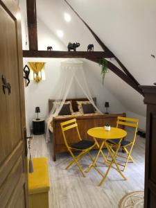 1 dormitorio con 1 cama, mesa amarilla y sillas en Un coin de paradis en Montpollin