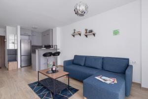 a living room with a blue couch and a table at Family Apartment with Parking & Terrace by Renters in Kraków