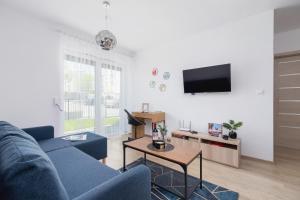 a living room with a blue couch and a tv at Family Apartment with Parking & Terrace by Renters in Kraków