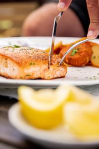 una persona cortando un trozo de pescado con un tenedor y un cuchillo en Posada Biarritz, en Canelones