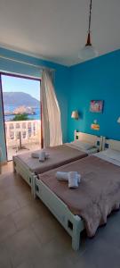 a blue bedroom with two beds and a large window at P i g a d i a B a y in Karpathos Town