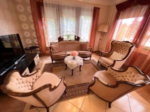 un soggiorno con sedie, TV e tavolo di RELAX Apartman a Nyíregyháza