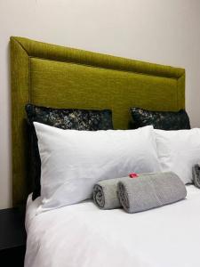 1 cama con almohadas blancas y cabecero verde en Matcha themed Apartment in City, en Johannesburgo