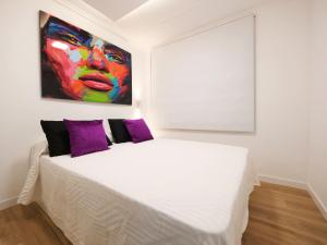 a bedroom with a white bed with a painting on the wall at Esmeralda Beach in Torrevieja +12 photos