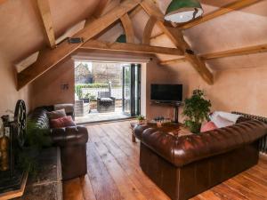 a living room with leather couches and a tv at Becket's Barn in Okehampton