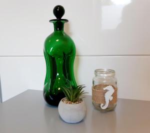 um frasco de vidro verde sentado numa mesa ao lado de uma planta em FeWo Greiwe em Telgte