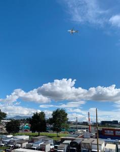 ein Flugzeug fliegt über einen Parkplatz mit Anhängern in der Unterkunft Bogotá Kings 401 in Bogotá