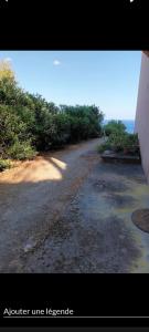 a dirt road next to a hill with the ocean at Studio plage in Santa-Maria-di-Lota