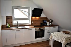eine Küche mit weißen Schränken, einem Waschbecken und einem Fenster in der Unterkunft Heiligenbergblick in Heidelberg
