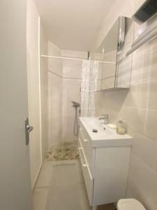 La salle de bains blanche est pourvue d'un lavabo et de toilettes. dans l'établissement Superbe T2 face mer 4EST402, au Barcarès