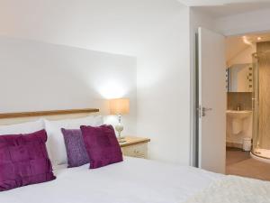 1 dormitorio con cama blanca y almohadas moradas en Balnacraig, en North Kessock