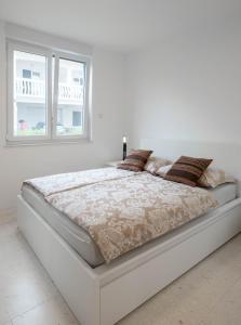 a bed in a white bedroom with a window at Apartment Dubravka in Povljana