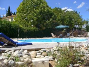 a swimming pool with a chair and an umbrella at DOMAINE DU SIESTOU WINE RESORT & spa in Laure-Minervois
