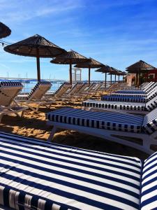 eine Gruppe von Stühlen und Sonnenschirmen am Strand in der Unterkunft Hotel La Potiniere in Hyères