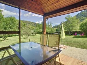 a glass table on a patio with a view of a field at Chalet grand jardin, au calme, proche commerces in La Canourgue