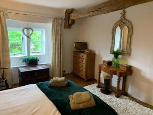 a bedroom with a bed and a dresser and a mirror at Crosse Chance Cottage - Idyllic, beautiful, traditional cottage to love - Wood burner in Taddington