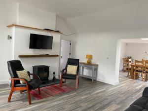 a living room with two chairs and a fireplace at Peg and Barrys Cottage near Fenit in Fenit