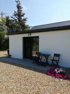 a white building with a table and chairs and flowers at Peg and Barrys Cottage near Fenit in Fenit