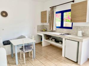 a kitchen with a counter and a table and a window at Lindos Athena in Lindos