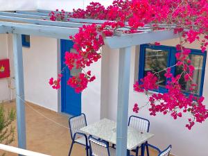 a table and chairs under a pergola with pink flowers at Lindos Athena in Lindos