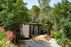 a tiny house with a porch and stairs at Camping Le Camp Du Domaine in Bormes-les-Mimosas