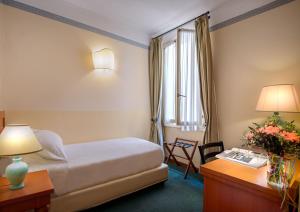 um quarto de hotel com uma cama, uma secretária e uma janela em Hotel Botticelli em Florença