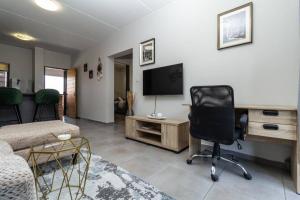 a living room with a chair and a desk with a television at Smart apartment 322 in Midrand