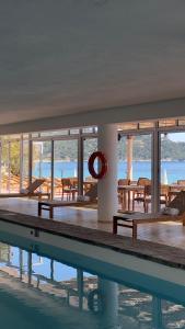 - une piscine avec des tables et des chaises dans un bâtiment dans l'établissement Surplage Hotel Cavalière, au Lavandou