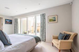 a bedroom with a bed and a chair and a window at No 10 in Cheltenham