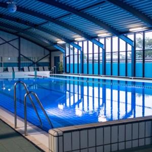una gran piscina cubierta con paredes y ventanas azules en Vakantiepark Klein Vaarwater, en Buren