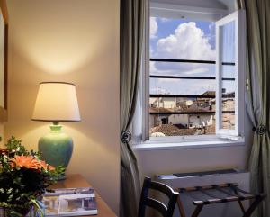 einen Schreibtisch mit einer Lampe und ein Fenster mit Aussicht in der Unterkunft Hotel Botticelli in Florenz