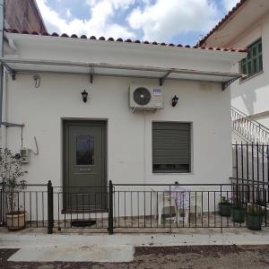 una casa bianca con una porta verde e una recinzione di Nikolas House - ΤΟ ΣΠΙΤΙ ΤΟΥ ΝΙΚΟΛΑ ad Archea Pissa