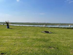 un parco con un'altalena nell'erba vicino a un corpo d'acqua di Maison avec piscine au milieu de la Baie d'Authie a Waben