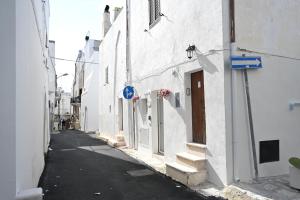 an alley with white buildings and a blue sign at CASA FLAMI' 4 in Ostuni