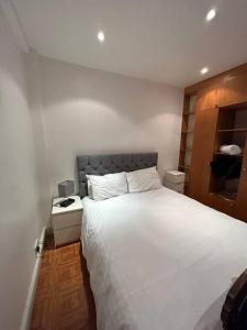 - une chambre avec un grand lit blanc et une table de nuit dans l'établissement Central London Apartment - H, à Londres
