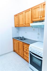 cocina con armarios de madera y horno de fogón blanco en Zois Apartments, en Nikiana