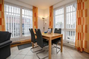 - une salle à manger avec une table, des chaises et des fenêtres dans l'établissement Dünenblick Wohnung 33, à Boltenhagen